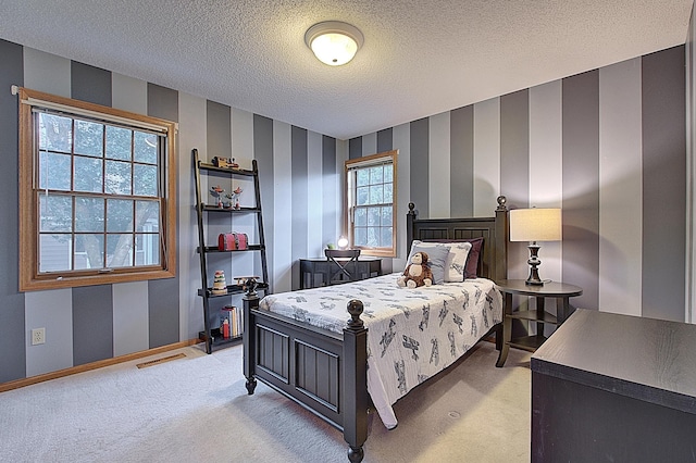 bedroom featuring a textured ceiling, light colored carpet, visible vents, baseboards, and wallpapered walls