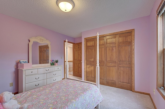 bedroom featuring a closet, light colored carpet, a textured ceiling, and baseboards