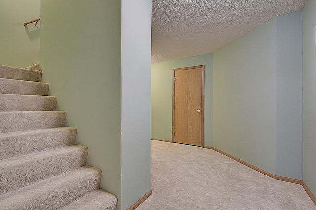 stairs with a textured ceiling, carpet floors, and baseboards