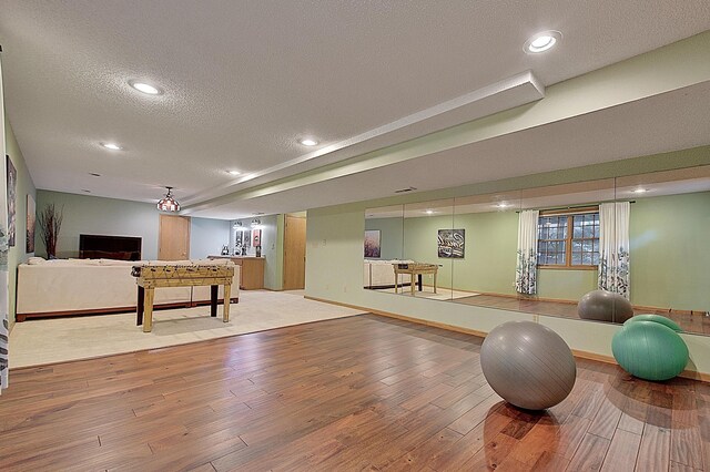 recreation room featuring a textured ceiling, baseboards, hardwood / wood-style floors, and recessed lighting