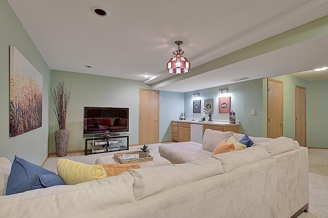 living room with light carpet, wet bar, baseboards, and a textured ceiling