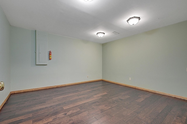 empty room with electric panel, dark wood finished floors, and baseboards