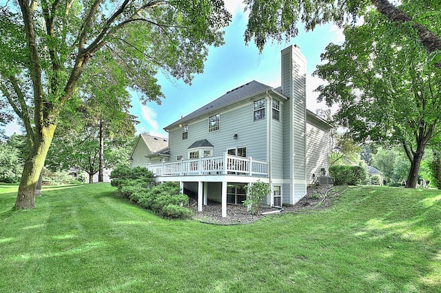 back of property featuring a lawn, a chimney, a wooden deck, and central air condition unit