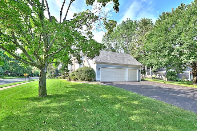 view of side of home featuring a yard, roof with shingles, and a detached garage