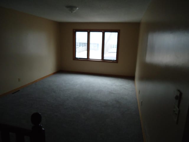 carpeted spare room featuring visible vents and baseboards