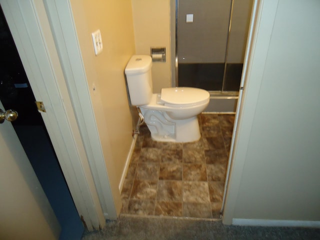 full bathroom with a stall shower, baseboards, and toilet