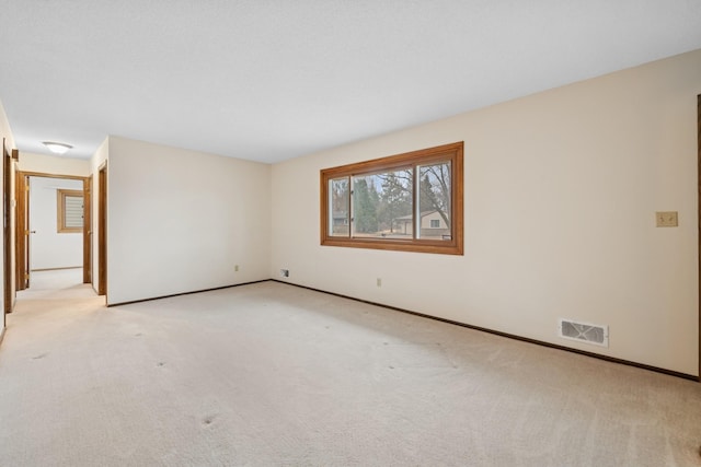 unfurnished room featuring light colored carpet, visible vents, and baseboards