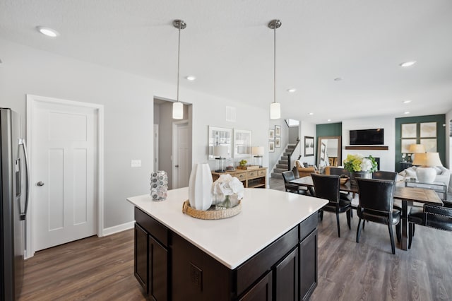 kitchen with dark brown cabinetry, stainless steel fridge with ice dispenser, open floor plan, decorative light fixtures, and light countertops