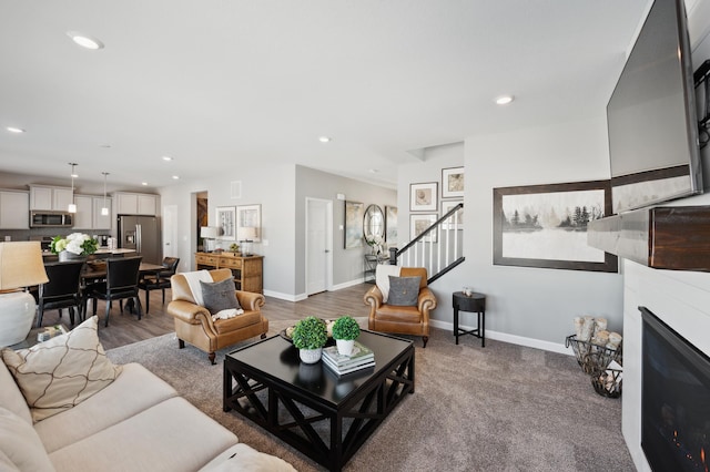 living room featuring a glass covered fireplace, baseboards, and recessed lighting