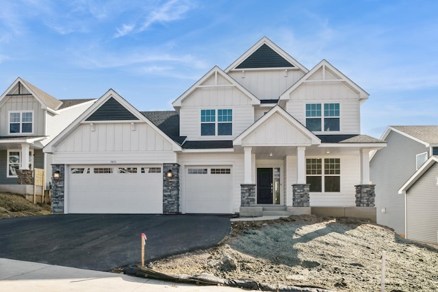 craftsman house with a shingled roof, a porch, board and batten siding, stone siding, and driveway