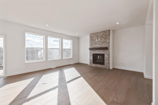 unfurnished living room with dark wood-style floors, a fireplace, baseboards, and recessed lighting