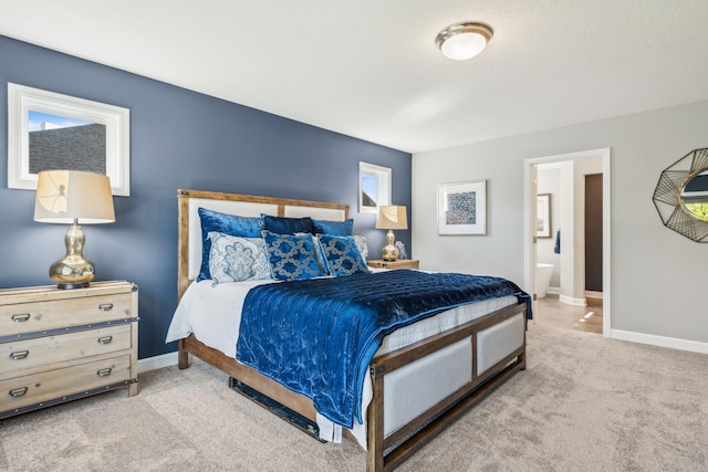 bedroom featuring ensuite bath, carpet, multiple windows, and baseboards