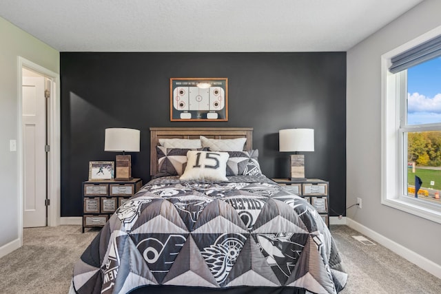 bedroom featuring an accent wall, carpet, visible vents, and baseboards