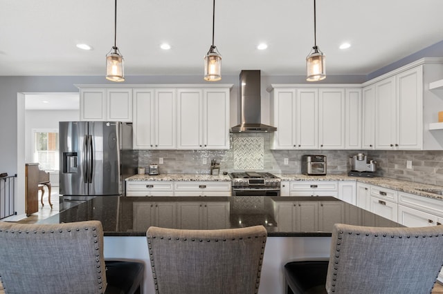 kitchen featuring hanging light fixtures, wall chimney range hood, appliances with stainless steel finishes, and a center island