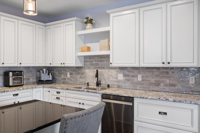 kitchen featuring pendant lighting, decorative backsplash, a sink, and white cabinets