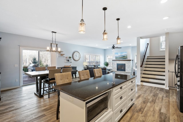 kitchen with hanging light fixtures, open floor plan, white cabinets, a kitchen island, and a kitchen bar