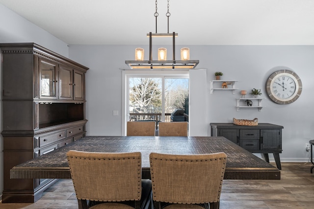 dining space with baseboards, a chandelier, and wood finished floors