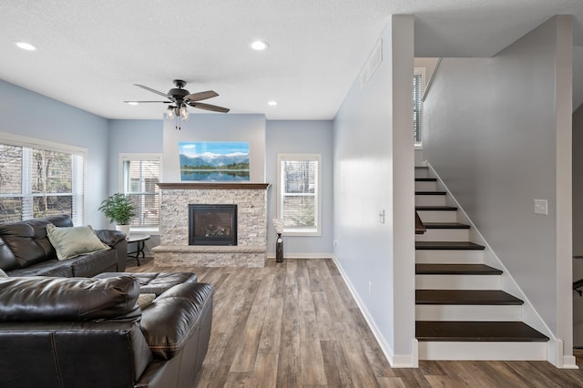 living room with stairs, a fireplace, baseboards, and wood finished floors