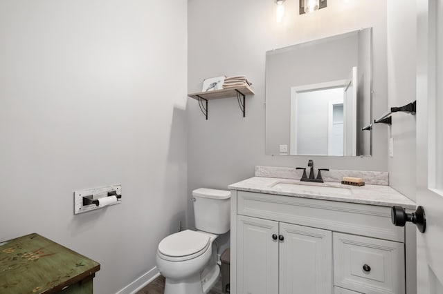 bathroom featuring toilet, baseboards, and vanity