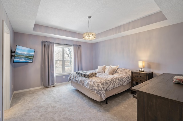 bedroom featuring light carpet, baseboards, a raised ceiling, and a textured ceiling