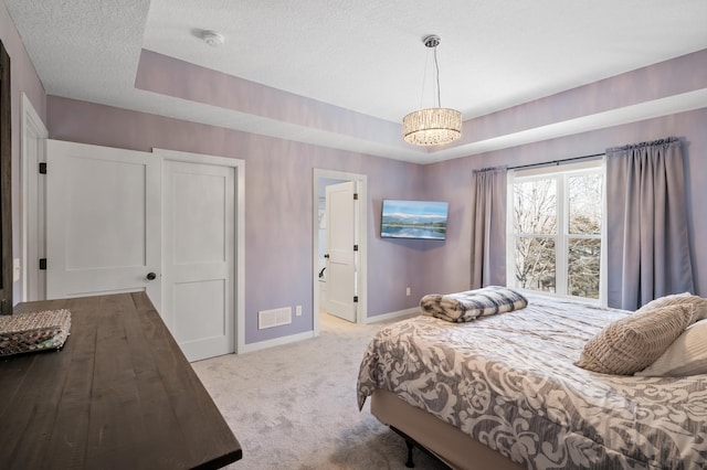 bedroom with baseboards, a textured ceiling, a raised ceiling, and light colored carpet