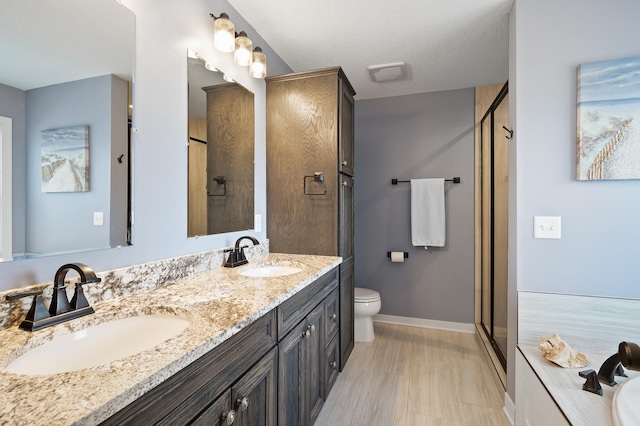 full bath with a sink, a shower stall, baseboards, and double vanity