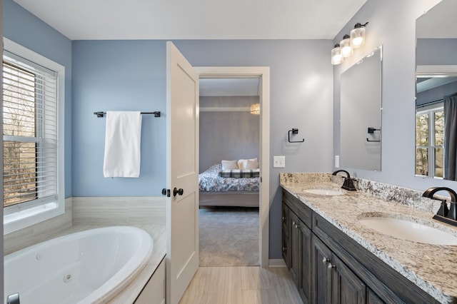 full bathroom featuring double vanity, a jetted tub, a sink, and connected bathroom