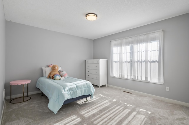 carpeted bedroom with visible vents, a textured ceiling, and baseboards