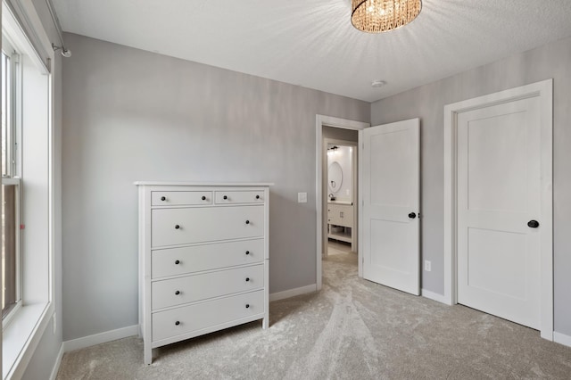 unfurnished bedroom with a textured ceiling, light colored carpet, and baseboards