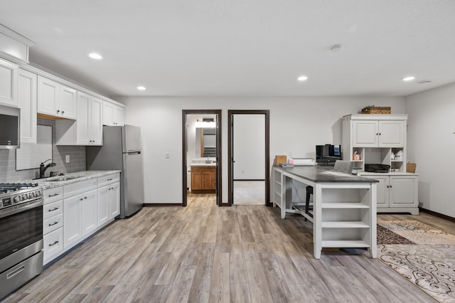 kitchen with decorative backsplash, white cabinets, stainless steel appliances, open shelves, and a sink