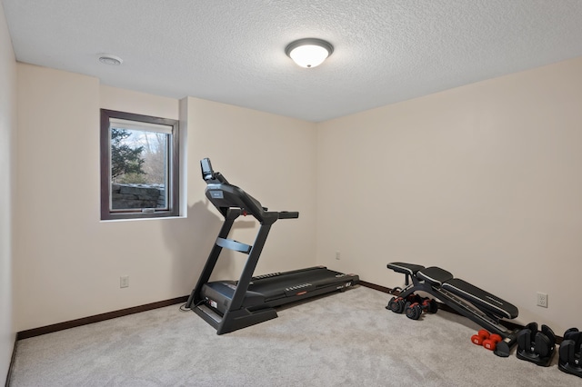 exercise area with a textured ceiling, carpet flooring, and baseboards