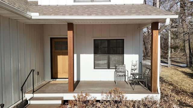 doorway to property featuring covered porch and roof with shingles