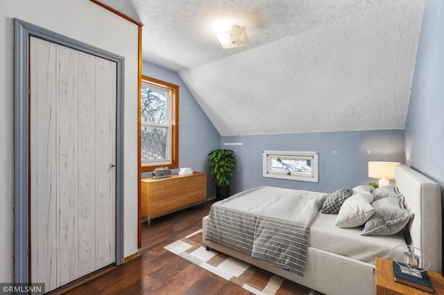 bedroom featuring a textured ceiling, vaulted ceiling, and wood finished floors