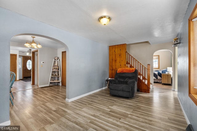 living area featuring stairs, arched walkways, baseboards, and wood finished floors