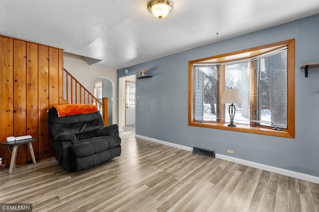 interior space with baseboards, visible vents, arched walkways, wood finished floors, and stairs