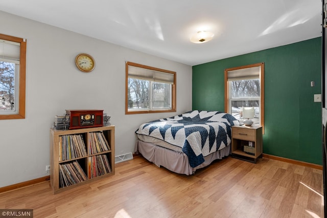 bedroom with light wood-style flooring, visible vents, and baseboards