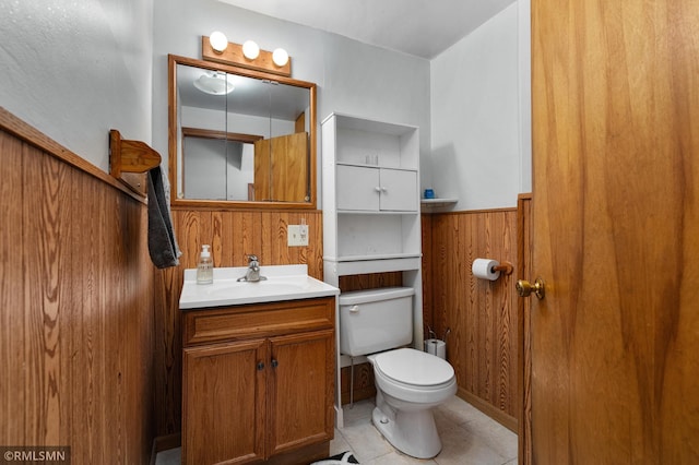 bathroom featuring wooden walls, vanity, toilet, and tile patterned floors