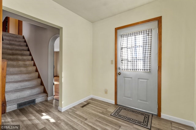 foyer entrance featuring visible vents, stairway, baseboards, and wood finished floors