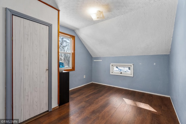 additional living space with lofted ceiling, hardwood / wood-style flooring, baseboards, and a textured ceiling