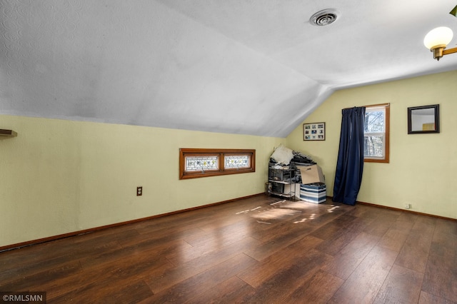 bonus room featuring lofted ceiling, baseboards, visible vents, and hardwood / wood-style floors