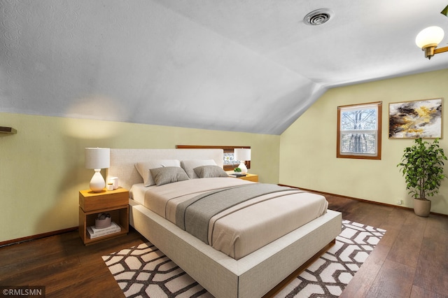 bedroom with multiple windows, visible vents, vaulted ceiling, and hardwood / wood-style floors