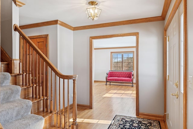 foyer entrance featuring stairs, crown molding, light wood-style floors, and baseboards