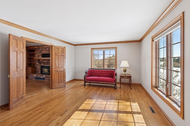 sitting room featuring visible vents, light wood finished floors, a fireplace, crown molding, and baseboards