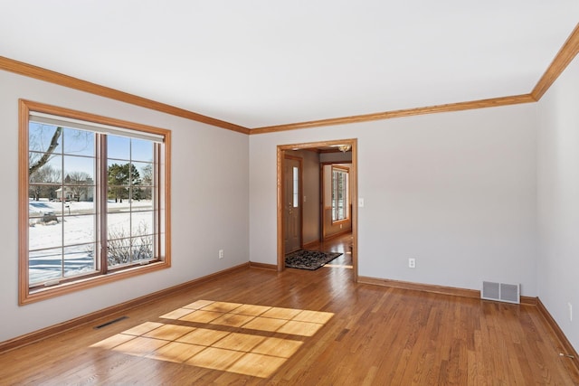 empty room with crown molding, wood finished floors, and visible vents