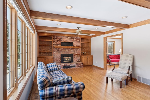 living area with beamed ceiling, baseboards, visible vents, and light wood-type flooring