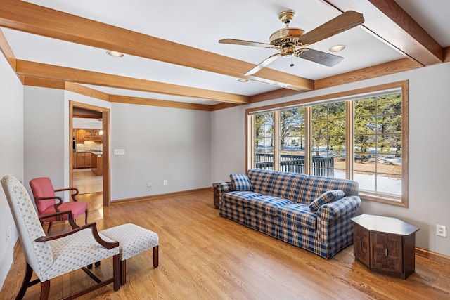 living area with beamed ceiling, ceiling fan, baseboards, and light wood-style floors