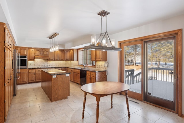 kitchen with decorative backsplash, brown cabinetry, appliances with stainless steel finishes, and a kitchen island