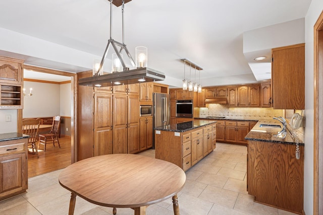 kitchen with a sink, a kitchen island, stainless steel appliances, dark stone counters, and decorative backsplash