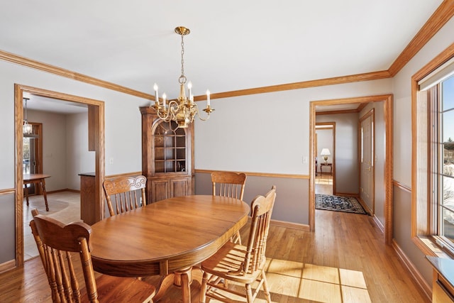 dining room featuring crown molding, baseboards, light wood finished floors, and a chandelier