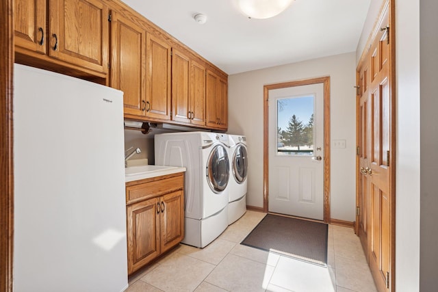 washroom with washer and clothes dryer, a sink, cabinet space, light tile patterned floors, and baseboards